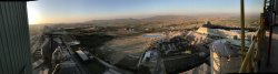 The view from the plant's preheater tower at dusk, with the clinker and cement silos on the left, the plant's orchards in the centre, raw meal silo and limestone shed at the right and the hills of the Salt Range in the distance.